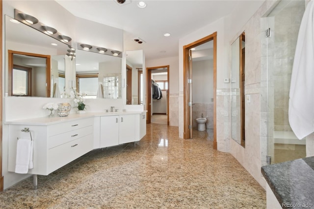 bathroom featuring vanity, a bidet, a shower with shower door, and tile walls