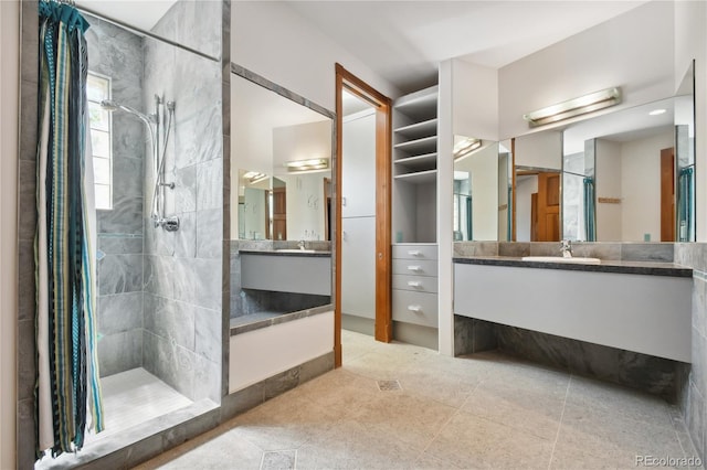 bathroom featuring tiled shower, vanity, and tile patterned flooring