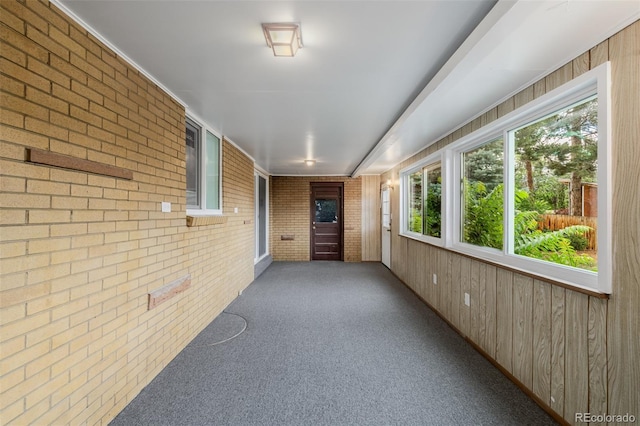 6994 Teller Ct, Arvada, CO 80003 - unfurnished sunroom with brick wall, wood walls, and carpet
