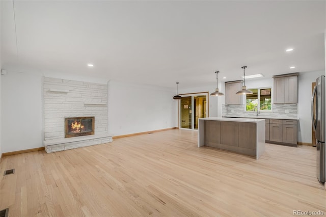 6994 Teller Ct, Arvada, CO 80003 - kitchen with open floor plan, light wood-type flooring, backsplash, a kitchen island, and light countertops