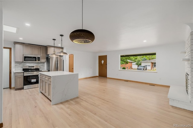 6994 Teller Ct, Arvada, CO 80003 - kitchen featuring stainless steel appliances, tasteful backsplash, light wood-style flooring, light countertops, and a center island