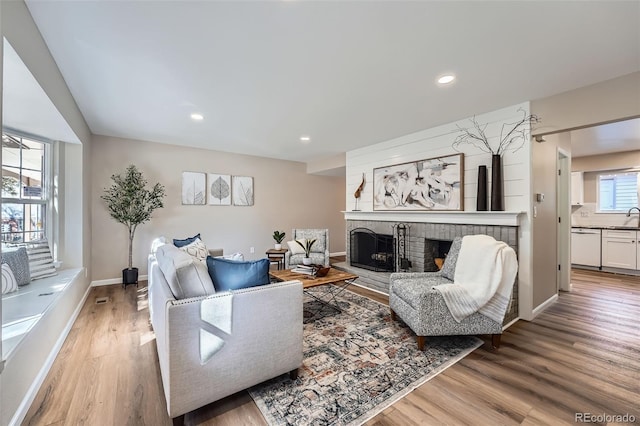 living room with light wood-style floors, recessed lighting, a fireplace, and baseboards