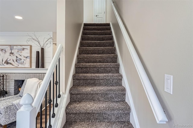 stairway with recessed lighting and a brick fireplace