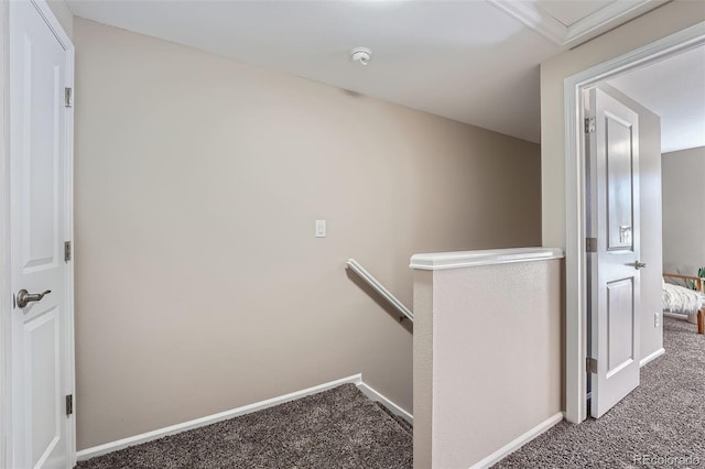 hall with carpet flooring, an upstairs landing, and baseboards