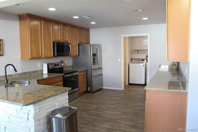 kitchen featuring sink, kitchen peninsula, stainless steel appliances, washer / clothes dryer, and light stone countertops