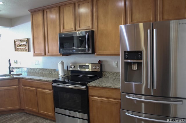 kitchen featuring light stone counters, appliances with stainless steel finishes, dark hardwood / wood-style floors, and sink