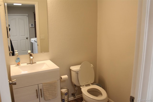 bathroom featuring vanity, washer and clothes dryer, and toilet