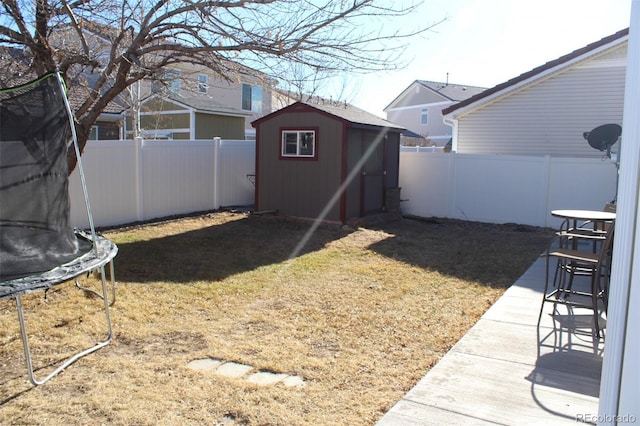 view of yard featuring a trampoline and a storage unit