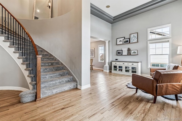 foyer entrance with a healthy amount of sunlight, a high ceiling, light hardwood / wood-style flooring, and ornate columns