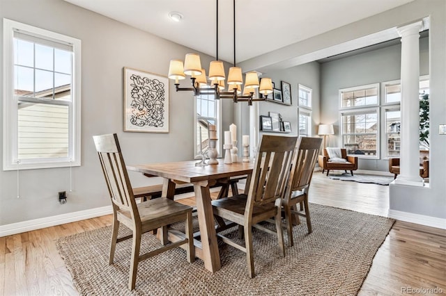 dining room with decorative columns, hardwood / wood-style flooring, and a chandelier