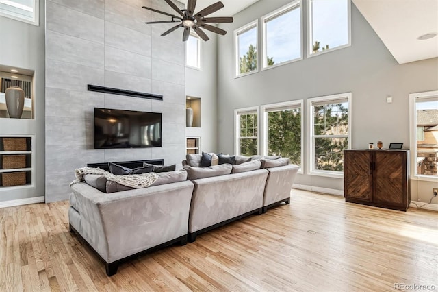 living room with a fireplace, a wealth of natural light, light hardwood / wood-style flooring, and ceiling fan