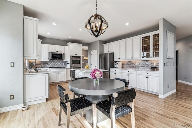 kitchen featuring stainless steel appliances, white cabinetry, pendant lighting, and light hardwood / wood-style floors