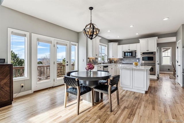 kitchen with a kitchen island, decorative light fixtures, white cabinetry, decorative backsplash, and stainless steel appliances