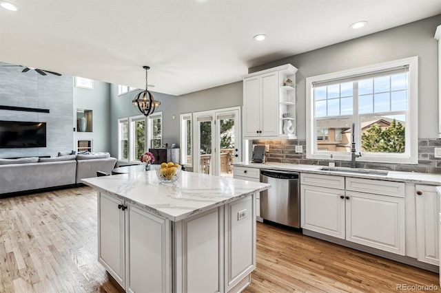 kitchen with sink, white cabinets, hanging light fixtures, a center island, and stainless steel dishwasher