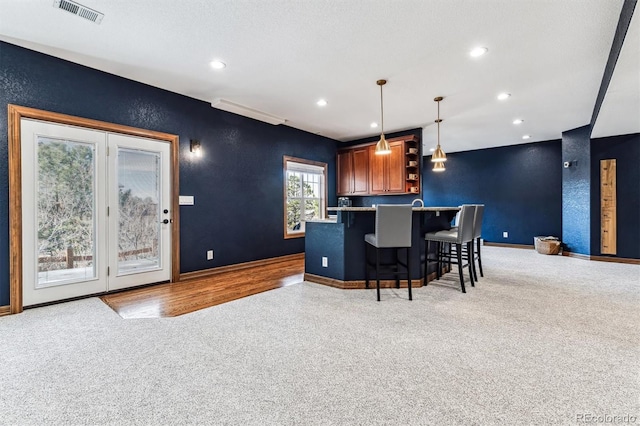 kitchen with pendant lighting, light colored carpet, a breakfast bar, and a textured ceiling