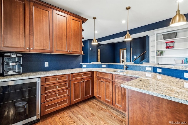 kitchen with pendant lighting, sink, wine cooler, light stone countertops, and light wood-type flooring