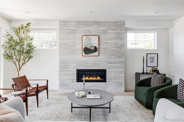 living room featuring a tile fireplace and light wood-type flooring