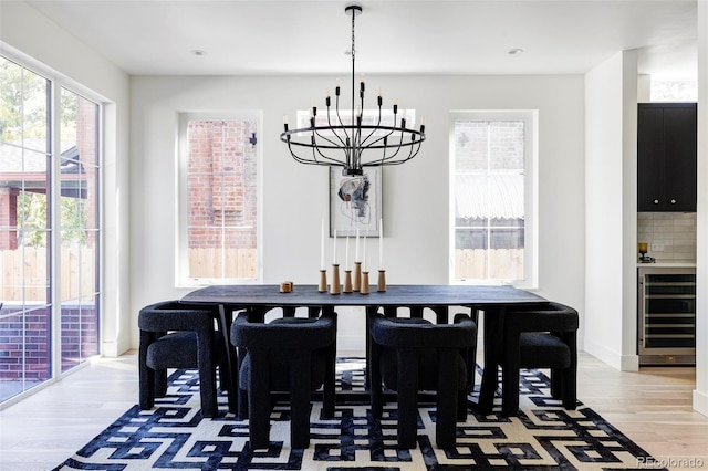 dining area featuring a notable chandelier, wood-type flooring, beverage cooler, and plenty of natural light