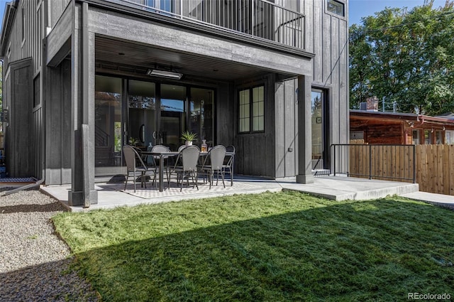 back of house featuring a patio, a lawn, and a balcony