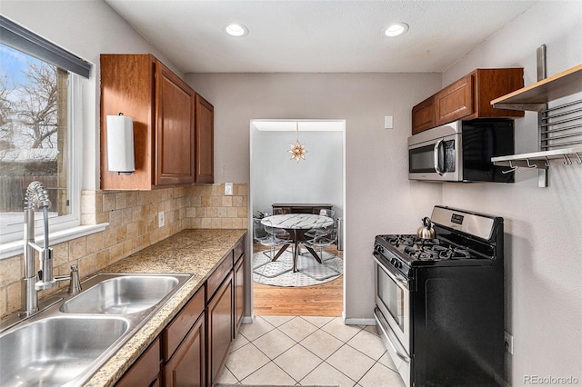 kitchen with brown cabinetry, a sink, stainless steel appliances, open shelves, and backsplash