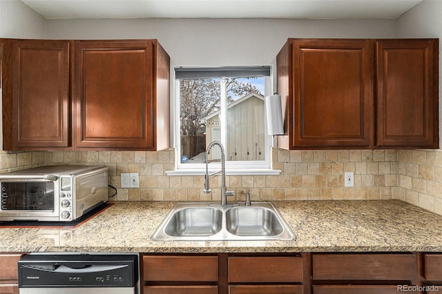 kitchen with light stone counters, a toaster, tasteful backsplash, a sink, and dishwasher