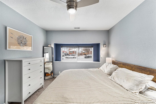 carpeted bedroom featuring a ceiling fan, visible vents, a textured ceiling, and a textured wall