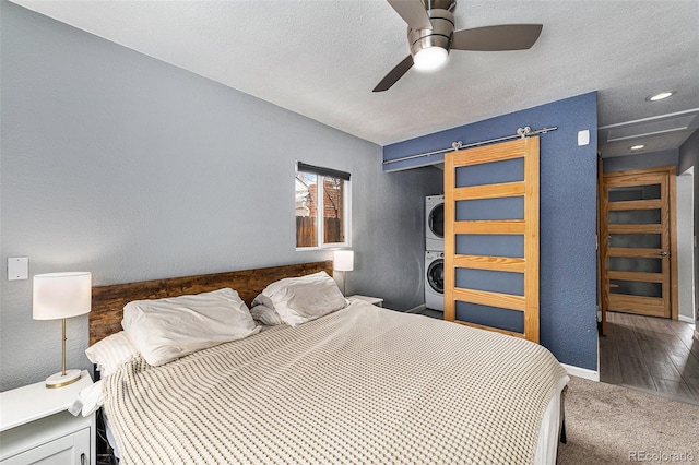 bedroom with a textured ceiling, a textured wall, carpet floors, baseboards, and stacked washer / drying machine