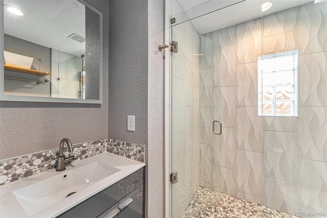 full bath with a shower stall, visible vents, a textured ceiling, and a textured wall