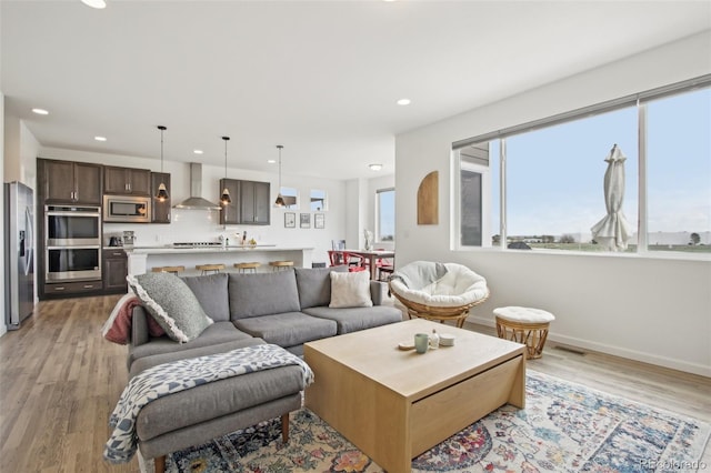 living room with recessed lighting, baseboards, and light wood finished floors