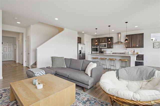 living area with baseboards, light wood-type flooring, and recessed lighting