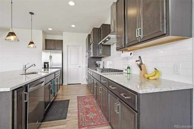 kitchen featuring dark brown cabinets, a sink, light wood finished floors, appliances with stainless steel finishes, and backsplash