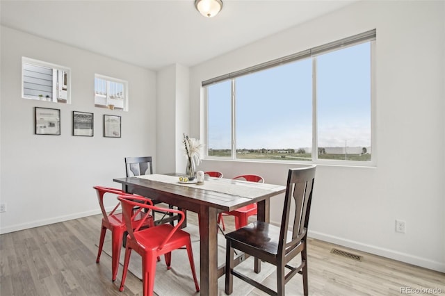 dining area with baseboards, visible vents, and light wood finished floors