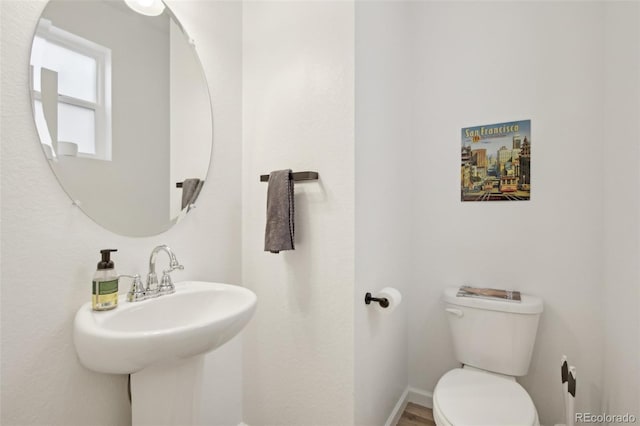 half bath featuring baseboards, a sink, and toilet