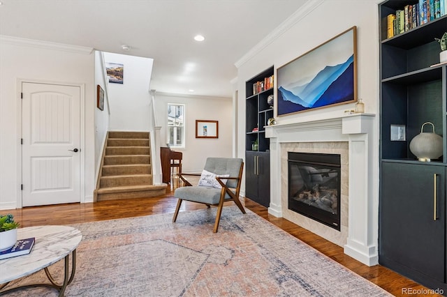 8695 E 49th Pl, Denver, CO 80238 - living area featuring crown molding, wood finished floors, stairs, built in shelves, and a glass covered fireplace