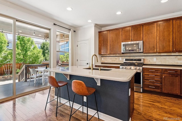 8695 E 49th Pl, Denver, CO 80238 - kitchen featuring stainless steel appliances, tasteful backsplash, ornamental molding, dark wood-type flooring, and a kitchen island with sink
