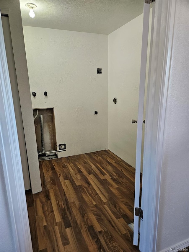 clothes washing area with dark hardwood / wood-style flooring and a textured ceiling