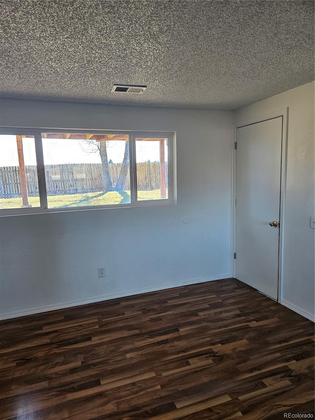 unfurnished room featuring dark hardwood / wood-style floors and a textured ceiling