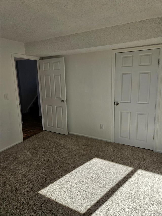 unfurnished room featuring a textured ceiling and dark colored carpet