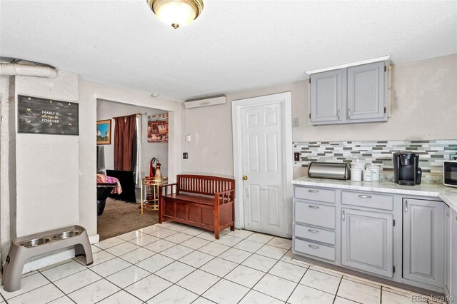 kitchen with a textured ceiling, decorative backsplash, light tile patterned flooring, and gray cabinets