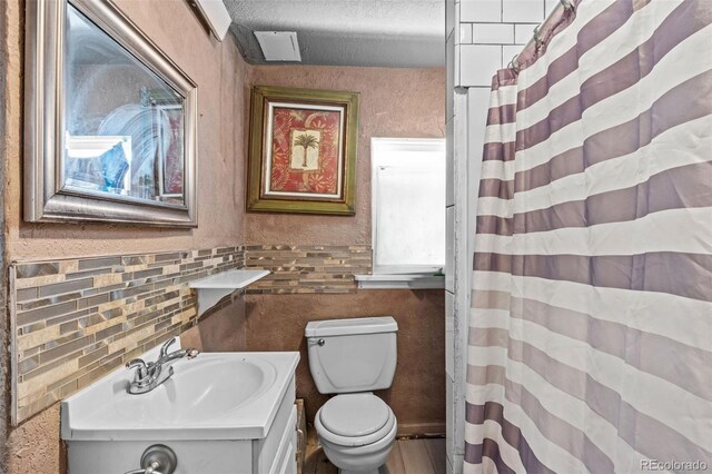 bathroom with a shower with curtain, a textured ceiling, vanity, and toilet