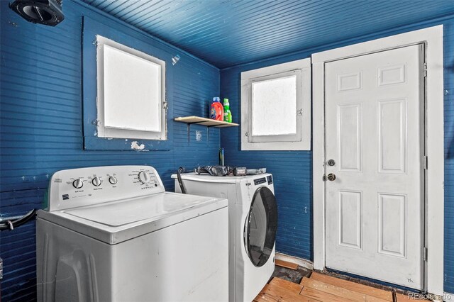 laundry area with light hardwood / wood-style floors, wooden walls, and independent washer and dryer