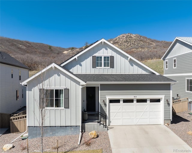 view of front facade featuring board and batten siding, a mountain view, a shingled roof, and driveway