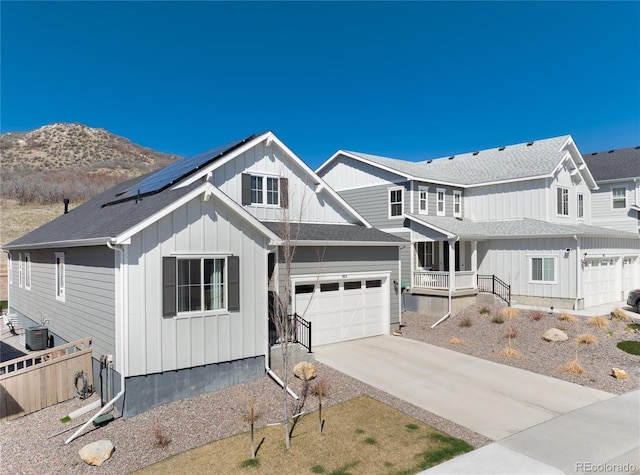 view of front of property with solar panels, covered porch, board and batten siding, fence, and driveway