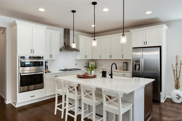 kitchen with dark wood-type flooring, decorative backsplash, wall chimney exhaust hood, and stainless steel appliances