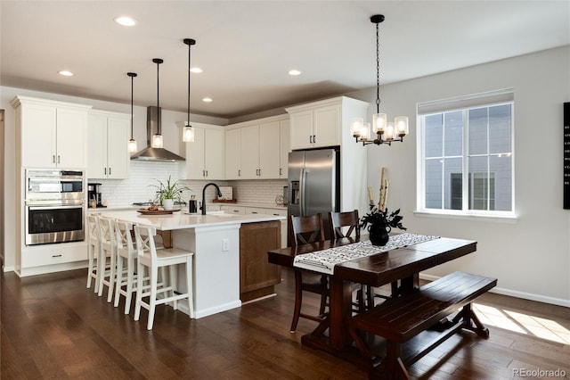 kitchen featuring tasteful backsplash, light countertops, wall chimney exhaust hood, and stainless steel appliances