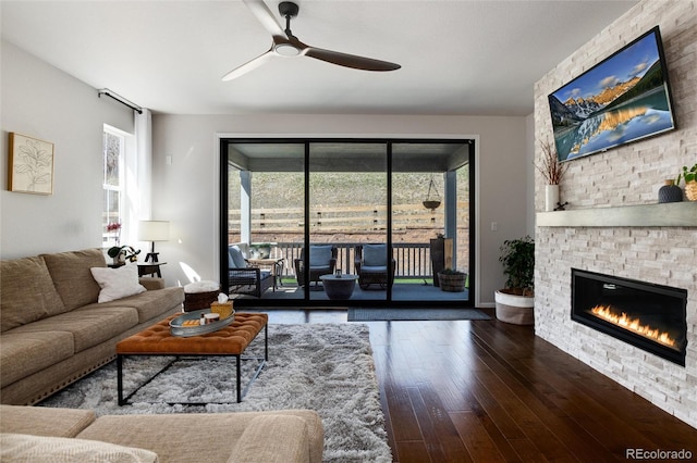 living room featuring a fireplace, wood-type flooring, and a ceiling fan