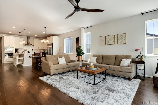 living room with ceiling fan with notable chandelier, dark wood-style floors, and recessed lighting