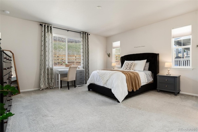 bedroom with baseboards, multiple windows, and light carpet