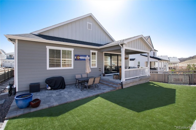 back of house featuring a shingled roof, board and batten siding, a patio area, and fence