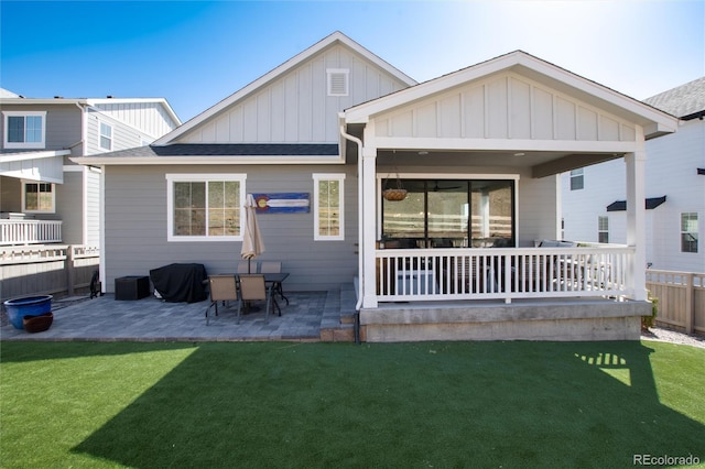 back of property featuring a yard, a patio, board and batten siding, and fence
